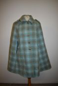 A 1960s Wetherall cape in pale blue and beige check.
