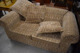 A modern settee in cream with maroon toned pattern
