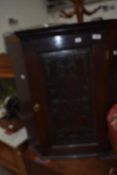 A Period oak corner wall cupboard having carved and poked decoration to door panel