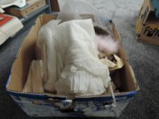 A box of dolls fabric, wigs, clothing and linen