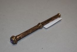A late Victorian propelling pencil having a rolled gold case with chase work design and purple glass