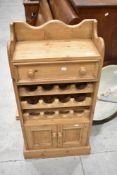 A natural pine wine rack having drawer over 12 bottle recess and cupboard to base