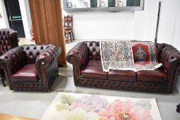 An oxblood red leather chesterfield and similar chair