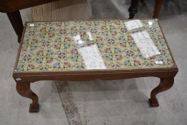 An early 20th Century coffee table having woolwork under glass to top