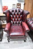 An oxblood red wing back armchair