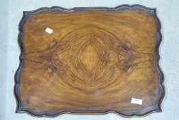 An early 20th Century walnut tray having shaped edge
