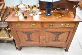 An Art Nouveau mahogany mahogany sideboard having stylised brass handles and carved panels