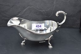 A silver sauce boat having loop handle, gadrooned rim and trefoil hoof feet, Birmingham 1972, Barker