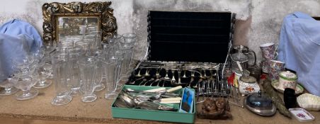 A gilt decorated wall mirror together with glass sundae dishes, other glasswares, cased flatware,