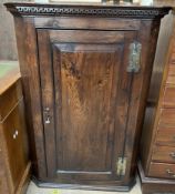 An 18th century hanging corner cabinet with a moulded dentil cornice above a single panelled door,