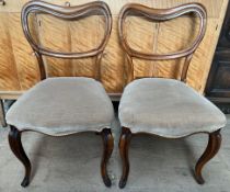 A pair of Victorian rosewood balloon back dining chairs with upholstered seats on shaped legs