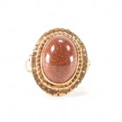 A 14ct gold and goldstone ring. The ring set with a goldstone cabochon ring having raised