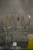 A pair of small gilt decorated and engraved wine glasses with double knop stems together with an