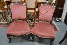 A pair of Victorian carved rosewood framed upholstered low chairs.
