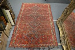 A Persian carpet, red ground with four central motifs.