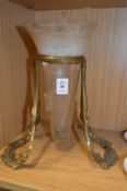A brass stand containing a conical glass vase.