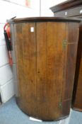 An oak and mahogany bow fronted hanging corner cupboard.