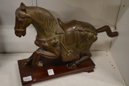 A Chinese cast bronze model of a horse on a hardwood stand.