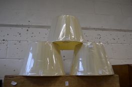 A set of three cream lampshades.