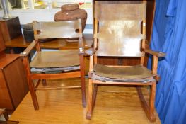 An unusual teak framed and leather upholstered rocking chair and matching armchair in the manner