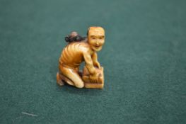 A small Japanese ivory netsuke of a crouching man.