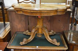 A Victorian walnut foldover card table of serpentine outline on a carved base (possibly reduced in