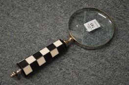 A magnifying glass with chequered handle.
