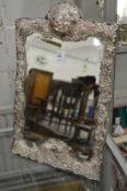 A dressing table mirror with silver embossed frame.