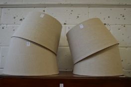 Four beige coloured lampshades.