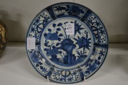A Chinese circular porcelain plate painted with panels of blue flowers.
