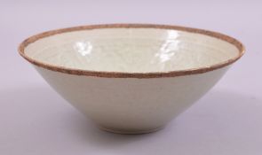 A CHINESE CELEDON GLAZED INCISED BOWL, the interior with carved floral decoration, 19.5cm diameter.