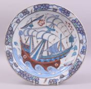 A LARGE IZNIK GLAZED POTTERY DISH, painted with a ship and waves with stylised fish, 31cm diameter.