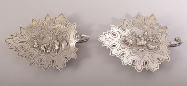 TWO INDIAN KUTCH SILVER LEAF FORM DISHES, the centre of each with embossed and finely chased scenes;