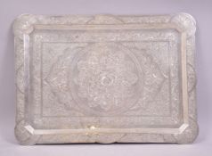 A PERSIAN WHITE METAL TRAY, of shaped rectangular form, profusely engraved with floral design,