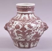 A CHINESE IRON RED AND WHITE GLAZED POTTERY VASE, with moulded handles and painted with native flora