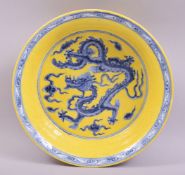 A CHINESE YELLOW GROUND PORCELAIN DRAGON BOWL, the centre painted with a dragon in blue with