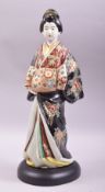A JAPANESE KUTANI PORCELAIN FIGURE, modelled as a standing geisha and mounted on a wooden base, 42cm