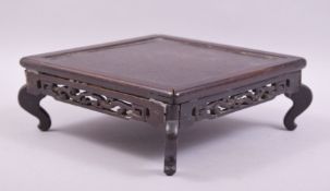 A CHINESE SQUARE FORM WOODEN STAND, supported on four curving legs, 20.5cm square, (af).