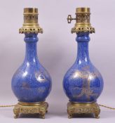A PAIR OF CHINESE BLUE GROUND AND GILT DECORATED PORCELAIN LAMPS / VASES with ormolu mounts, the