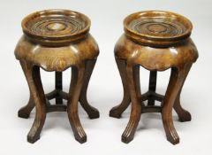 A PAIR OF CHINESE OAK CIRCULAR STANDS with turned, dished tops, supported on five curving legs