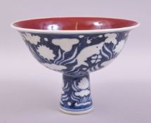 A CHINESE BLUE AND WHITE PORCELAIN STEM CUP, the exterior decorated with fish and flora, the