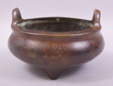 A CHINESE BRONZE TWIN HANDLE TRIPOD CENSER, with four character mark to base, 15cm diameter.