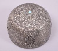 AN INDIAN WHITE METAL DOME SHAPED BOX, with hinged cover, repouse decorated, inset with a