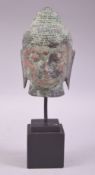 A SOUTH EAST ASIAN METAL BUDDHA HEAD, raised upon a wooden stand, 12cm high.