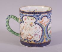 A CHINESE CLOBBERED PORCELAIN MUG / TANKARD, painted with three panels depicting outdoor settings