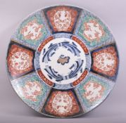 A LARGE JAPANESE IMARI PORCELAIN CHARGER, painted with floral panels in the imari pallette, the