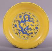 A CHINESE YELLOW GROUND PORCELAIN DRAGON DISH, the centre painted in blue with a roundel