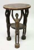 AN UNUSUAL AFRICAN HARDWOOD STOOL, the circular top supported by three figures with arms
