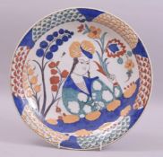 A PERSIAN IRANIAN GLAZED POTTERY DISH, centre painted with a figure holding a flower, 30cm