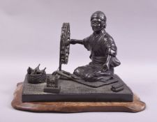 A GOOD JAPANESE BRONZE GROUP modelled as a lady kneeling beside a spinning wheel with a basket of